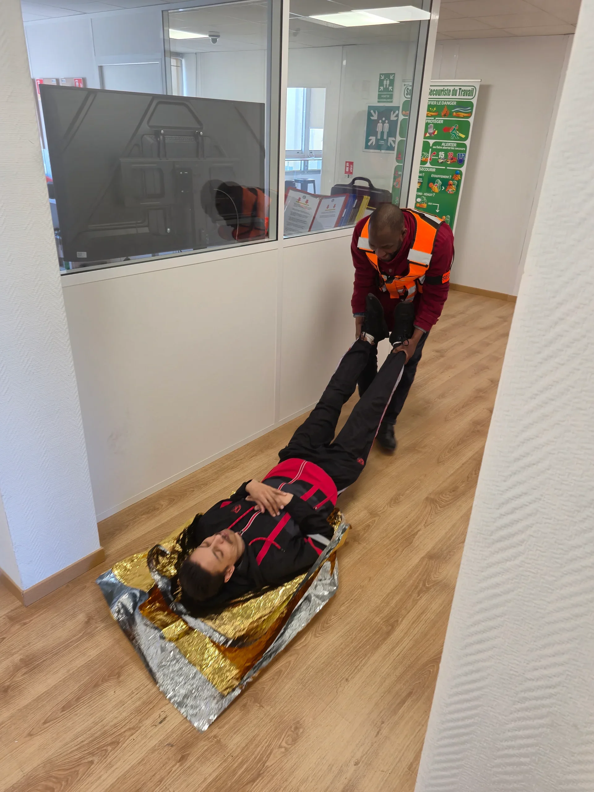 Victime allongée sur une couverture de survie, tractée par un stagiaire