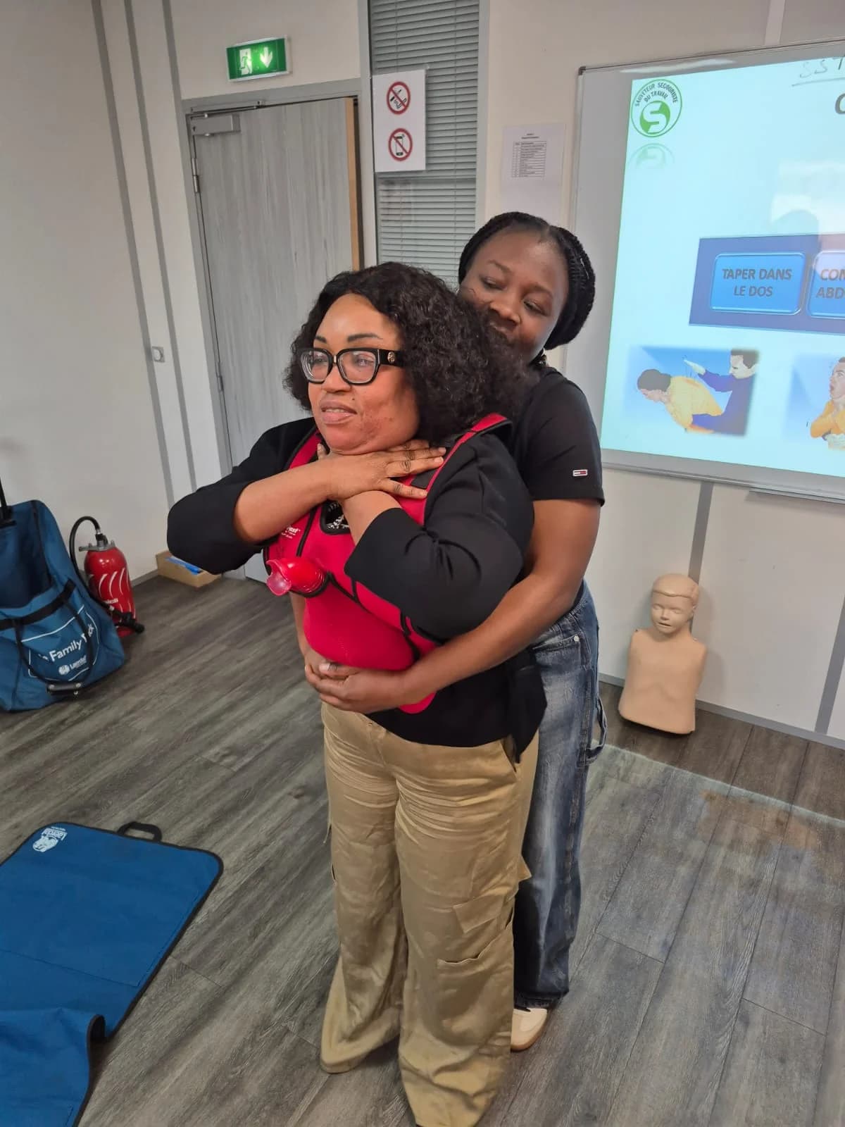 Stagiaire réalisant des compressions abdominales sur une partenaire qui simule un étouffement