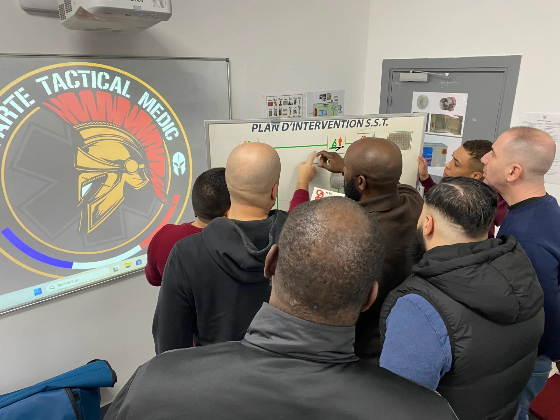 Groupe de stagiaires face au tableau présentant le plan d'intervention SST