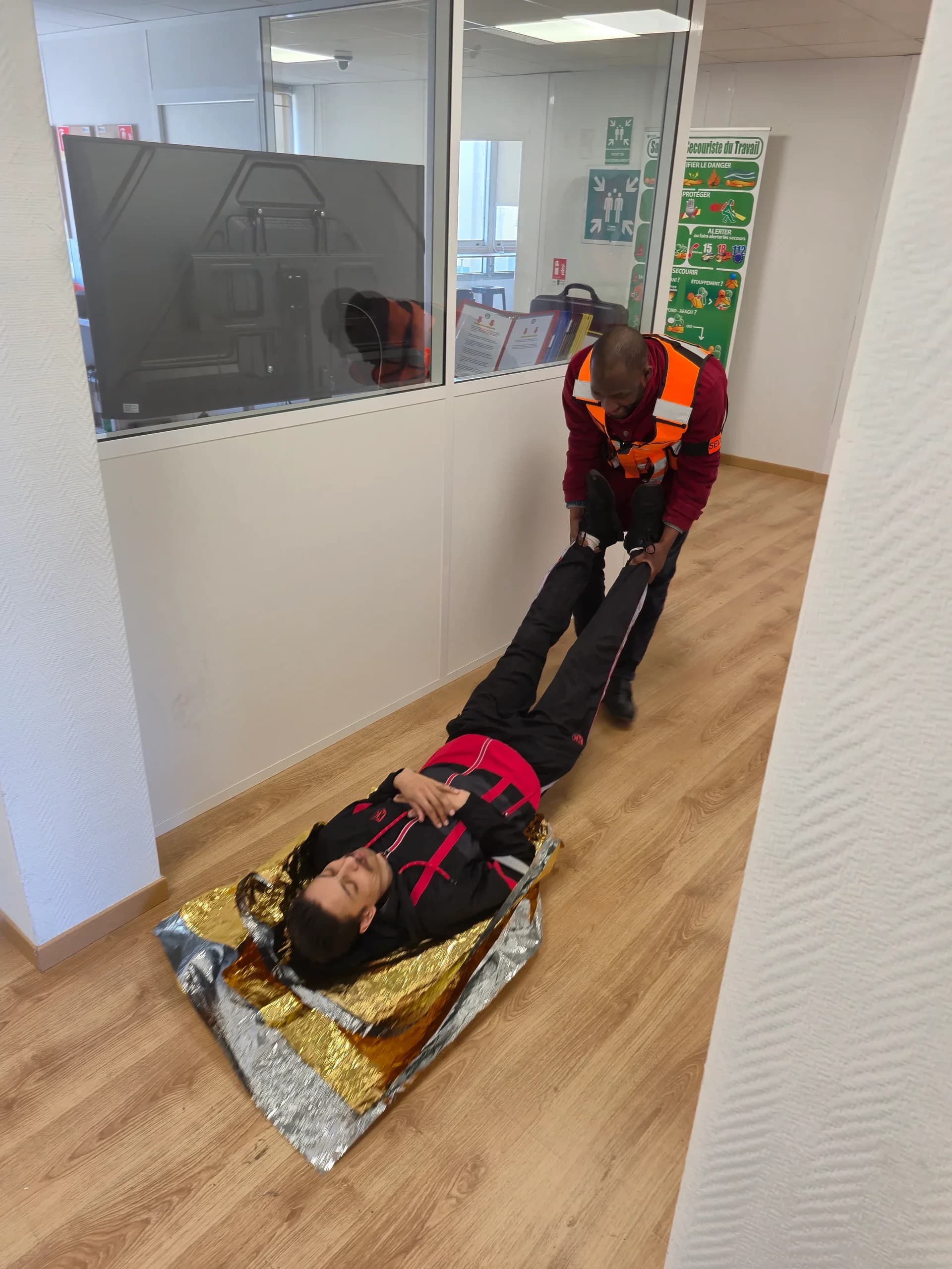 Victime allongée sur une couverture de survie, tractée par un stagiaire