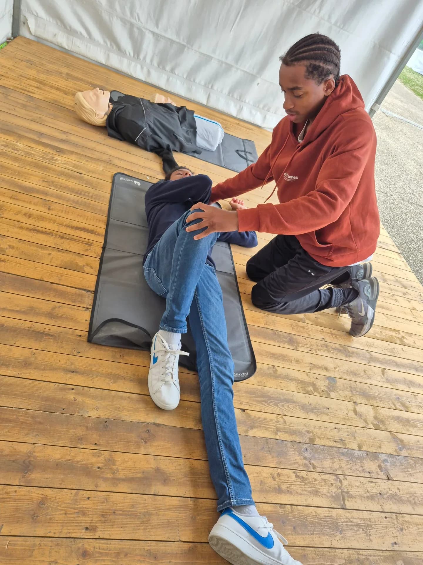 Stagiaire fléchissant la jambe d'une victime pour la mettre en position latérale de sécurité